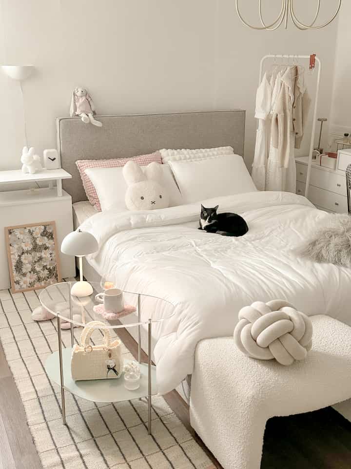 Bright white and natural tone bedroom featuring a cozy bed with plush bedding and soft decor elements