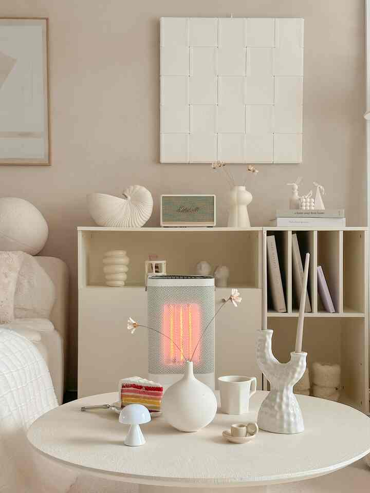 ベージュトーンのリビング、白いソファと丸いコーヒーテーブルにミニマルな花瓶や小物が配置された落ち着いた空間