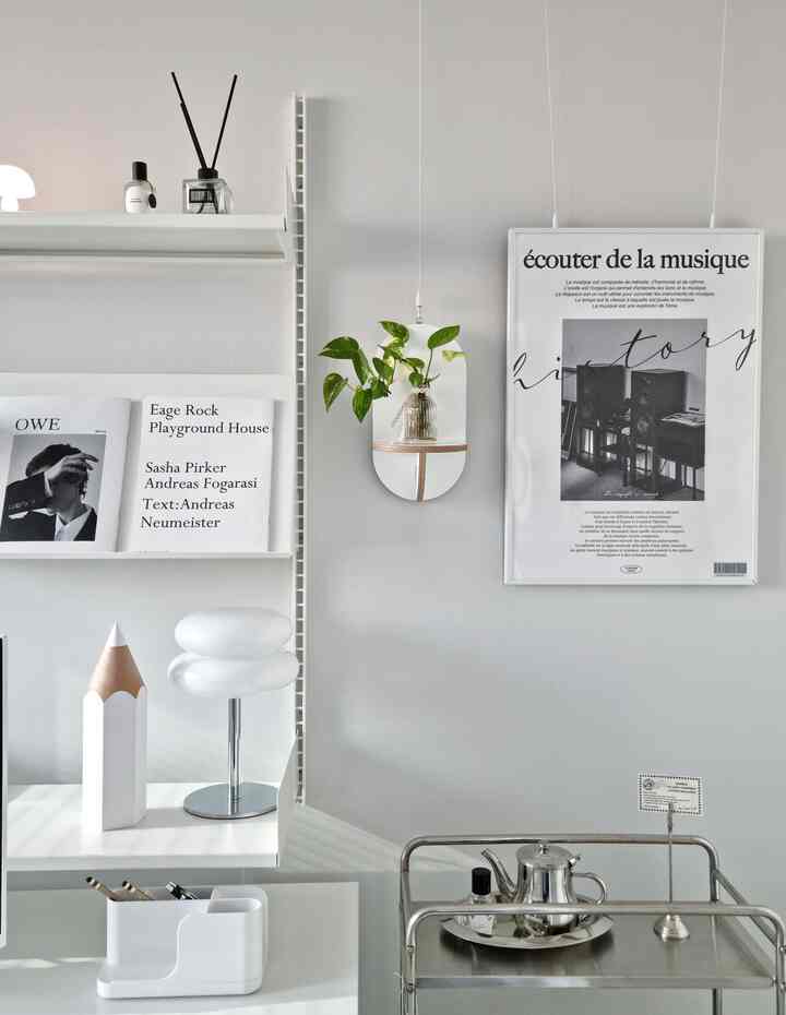 White-toned study-style home office featuring wall shelves, a mid-century modern trolley, and neatly arranged desk supplies