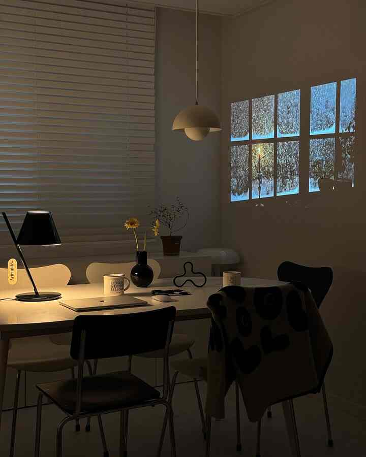 Modern home office space dominated by white and black tones, featuring a dining table with chairs creating a cozy atmosphere.