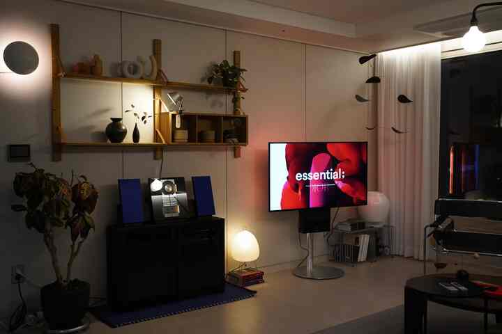 A modern living room with warm wood tones and beige walls, featuring pendant and floor lamps that create a cozy ambiance