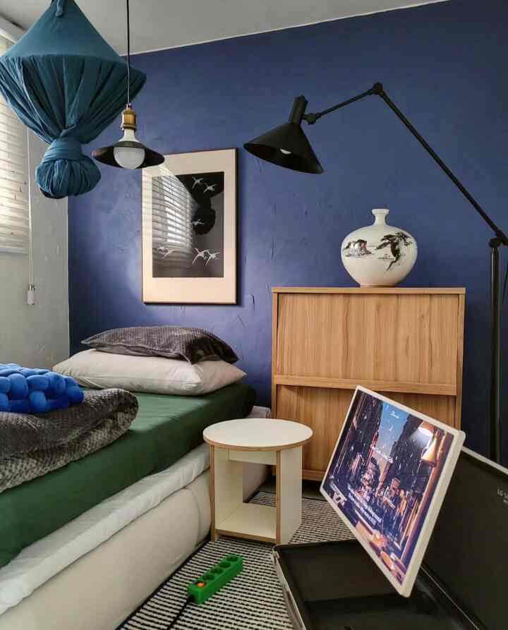 Kids' bedroom with deep blue accent wall and wood tone cabinet, featuring modern and tidy interior design