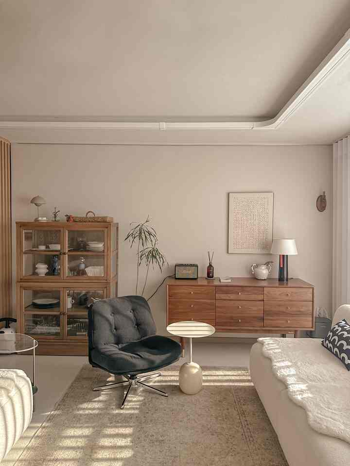 Cozy and clean living room with warm beige and natural wood tones, featuring a sofa, armchair, and rug