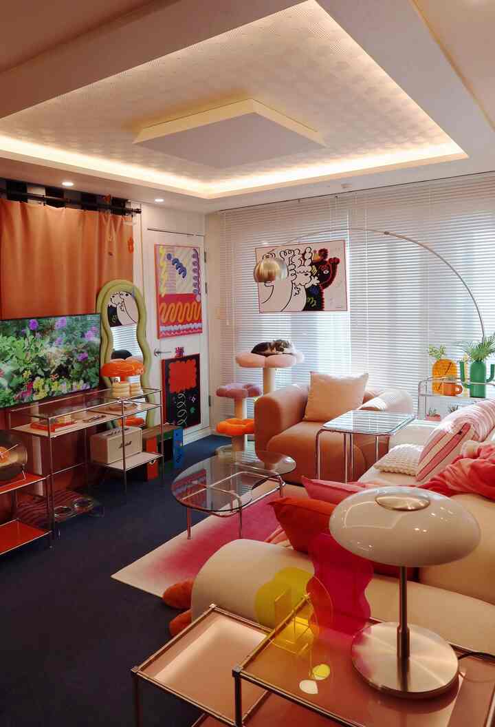 Pink-toned living room featuring sofa, side tables, cat tower, and picture frames creating a modern and cozy atmosphere