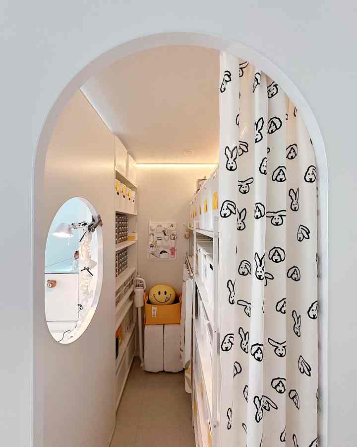 White-toned narrow and neatly organized pantry room featuring multiple storage boxes and shelves creating a cozy space