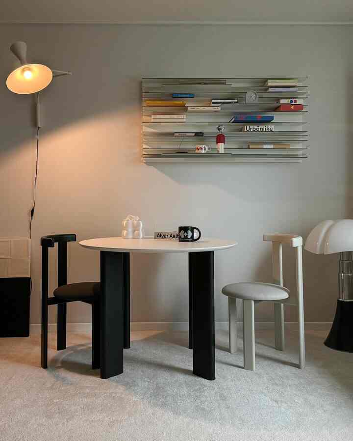 Bright, simple-toned living room featuring a white round table with black and white chairs in a modern setting