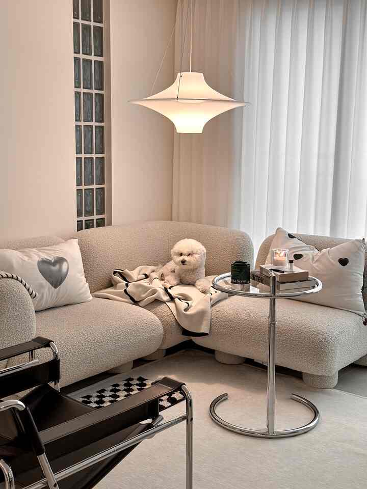 白とグレーのトーンのリビング、ブークレのモジュールソファとペットの犬がくつろぐモダンな空間