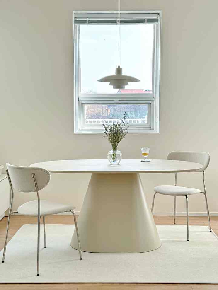 白とベージュのトーンのシンプルなダイニング、セラミックのダイニングテーブルとペンダントライトが配置された雰囲気のある自然なモダンインテリア