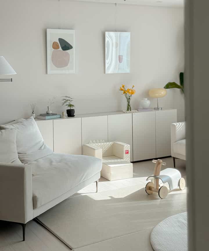 明るくナチュラルカラーのリビング、ホワイトソファと赤ちゃん用家具が配置された清潔感と温かみのあるインテリア