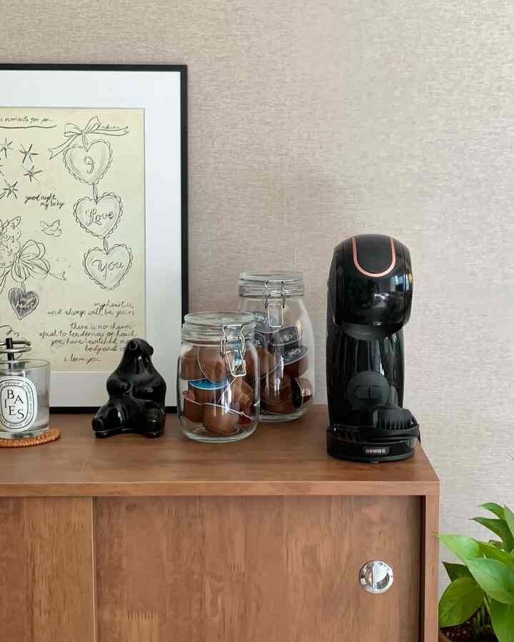 ベージュの壁と木製キャビネットが配置されたおうちカフェ、コーヒーマシンと密閉ガラス容器が整然と並ぶ雰囲気のあるインテリア