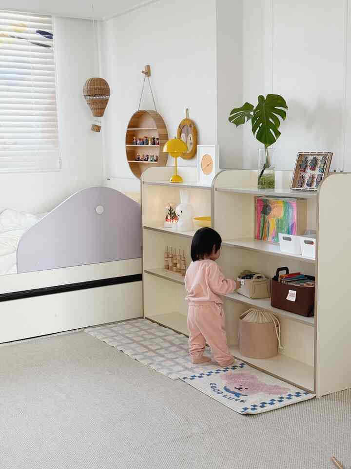 白とナチュラルカラーの子供部屋、子供用ベッドと収納棚が配置された、落ち着いた整理されたインテリア