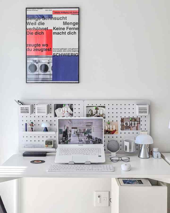 白を基調としたホームオフィス、中央に配置されたデスクとペグボード、ノートパソコンと照明が整然とした印象的な空間を演出