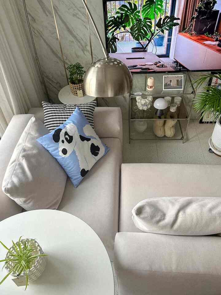 White and silver toned living room featuring beige sofa and metal floor lamp with a modern and natural atmosphere