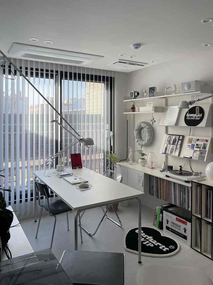 モノトーン調のコンパクトなホームオフィス、白いデスクと黒の椅子、壁付け収納と大型の壁時計が配置されたモダンな空間