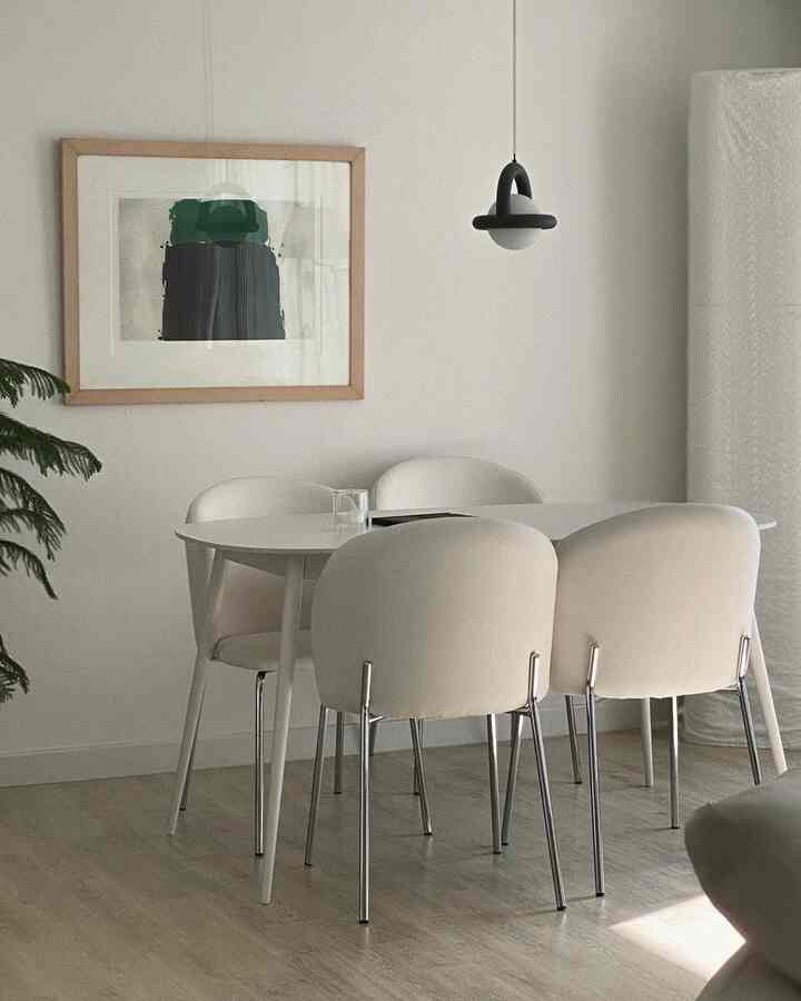 Natural and white toned dining room featuring white dining table and chairs with a black pendant light, creating a simple modern atmosphere