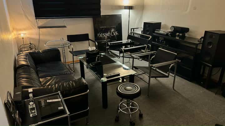 黒を基調としたリビング、レザーソファとメタルフレームチェア、ガラステーブルが配されたモダンでミッドセンチュリーモダンな印象的な空間