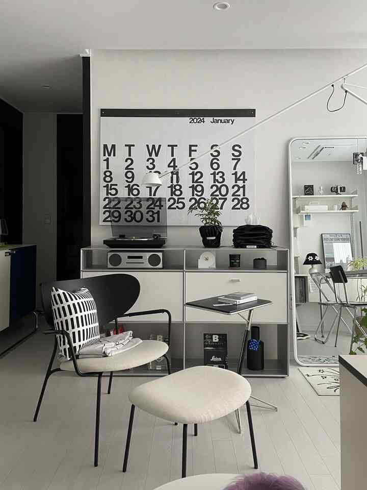 Modern living room in white and black tones featuring a Stendig calendar and lounge chair in a stylish home office setup