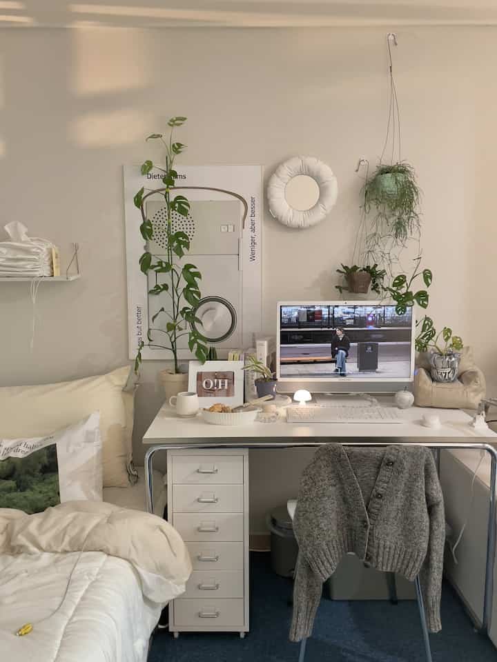 Bright white and wood-toned single household home office space featuring plants and a Mid-Century Modern poster, creating a cozy and neat desk environment