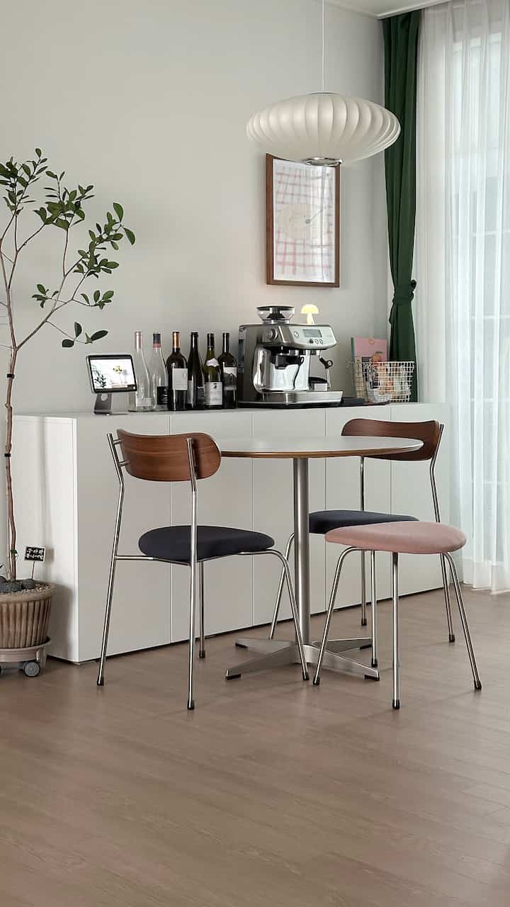 White and green toned dining room featuring a pendant light, round table, and an espresso machine creating a cozy home cafe vibe