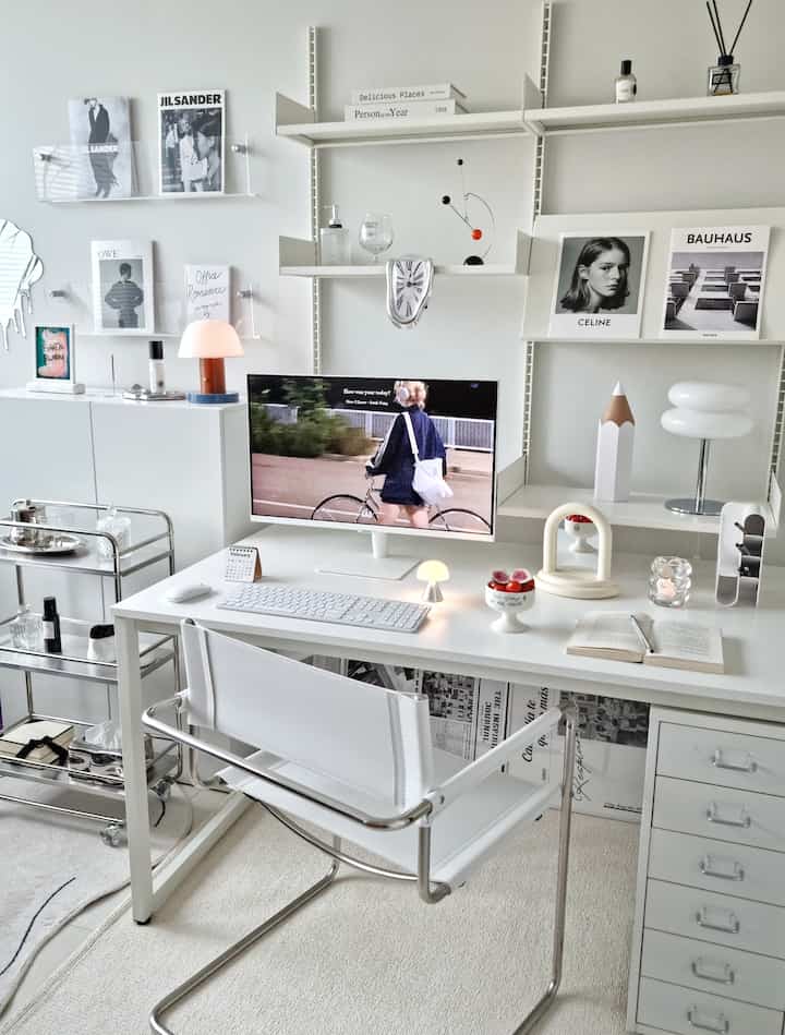 Bright white tone home office featuring modern desk and chair with various decorative objets creating a clean workspace