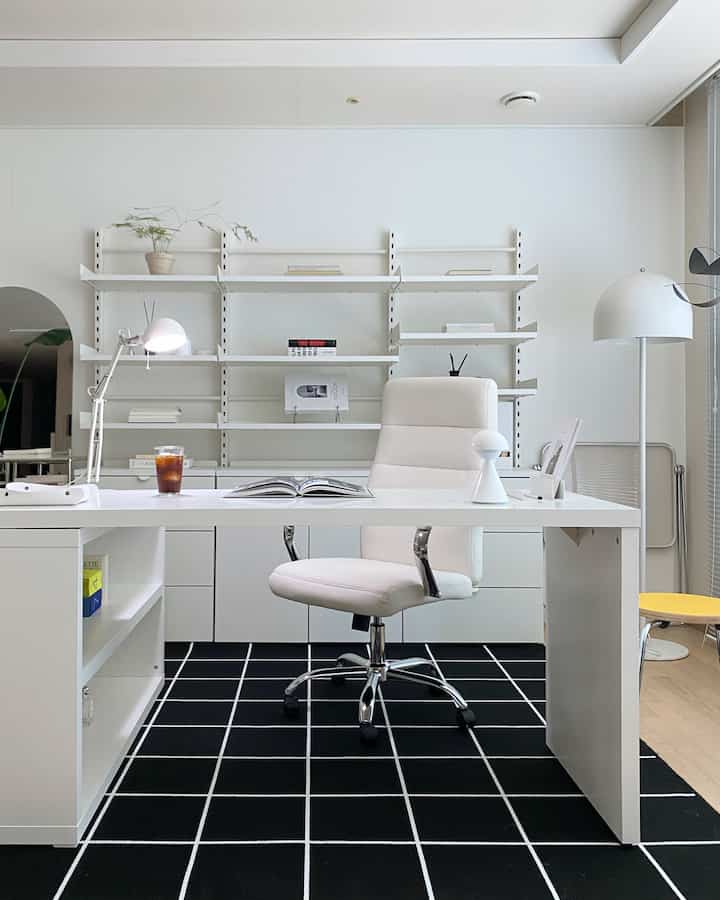 Minimal home office in white and black tones featuring a desk and office chair centrally placed