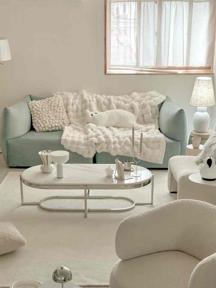 ベージュとパステルブルーのトーンのリビング、ソファとアームチェア、コーヒーテーブルが配された雰囲気のある空間