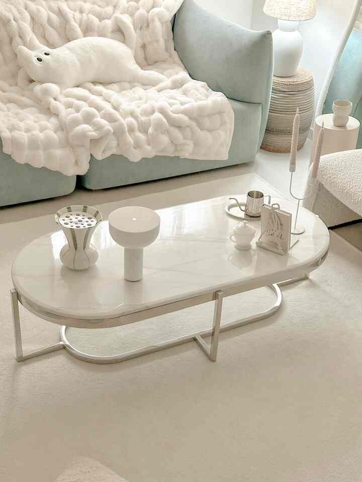 Bright white and pastel toned living room featuring a sofa and marble coffee table creating cozy atmosphere