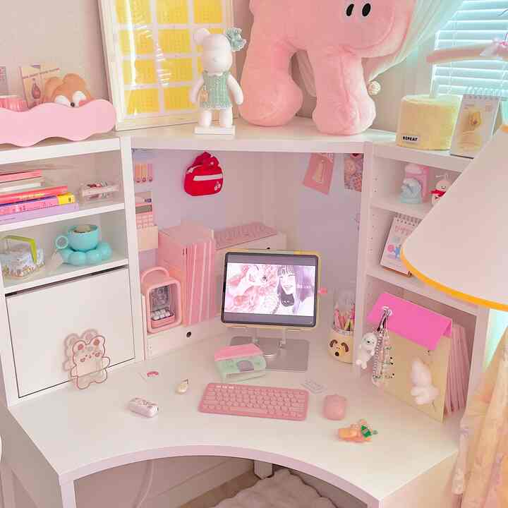 Cozy corner home office with white tones and pink accents, featuring a clean desk and organized shelving