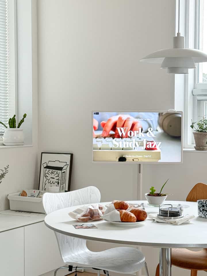 白を基調としたキッチンスペース、丸いダイニングテーブルとモダンな椅子、テーブルの上にはクロワッサンが置かれた居心地の良いおうちカフェの雰囲気