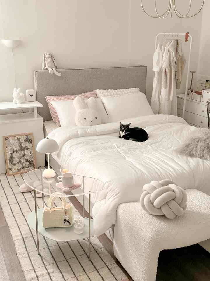 White and beige toned bedroom featuring a large bed with a cat resting centrally, creating a cozy natural interior space