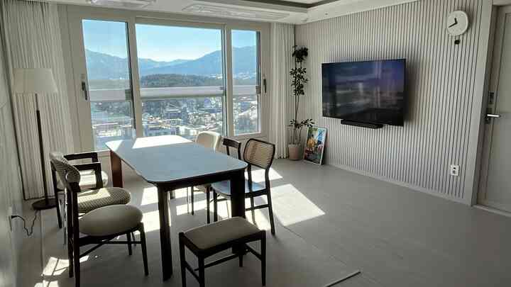 Bright white and wood-toned living and dining space featuring café-style dining table and chairs, creating a cozy home cafe atmosphere