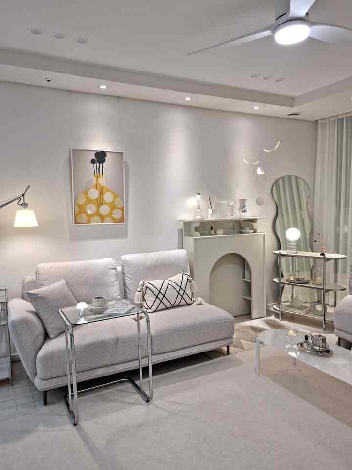 White-toned modern living room featuring a fabric sofa and glass sofa table with a clean, cozy atmosphere