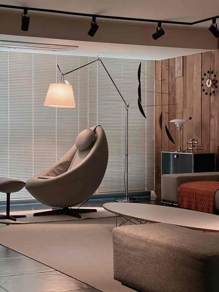 Cozy living room with warm wood accent wall and orange throw, featuring a modern floor lamp and decorative mobile