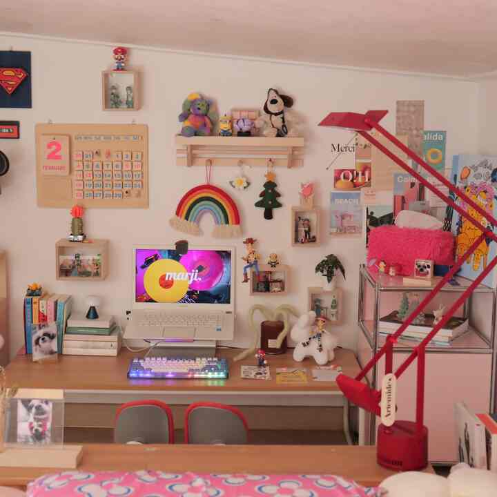 暖かみのある木目調と白い壁のホームオフィス、色鮮やかな小物と赤いテーブルランプが置かれた雰囲気ある作業空間