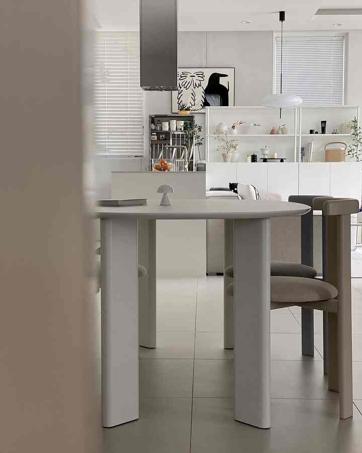 白とベージュの色調のキッチン、楕円形のダイニングテーブルとモダンな椅子が配置されたシンプルで洗練されたインテリア