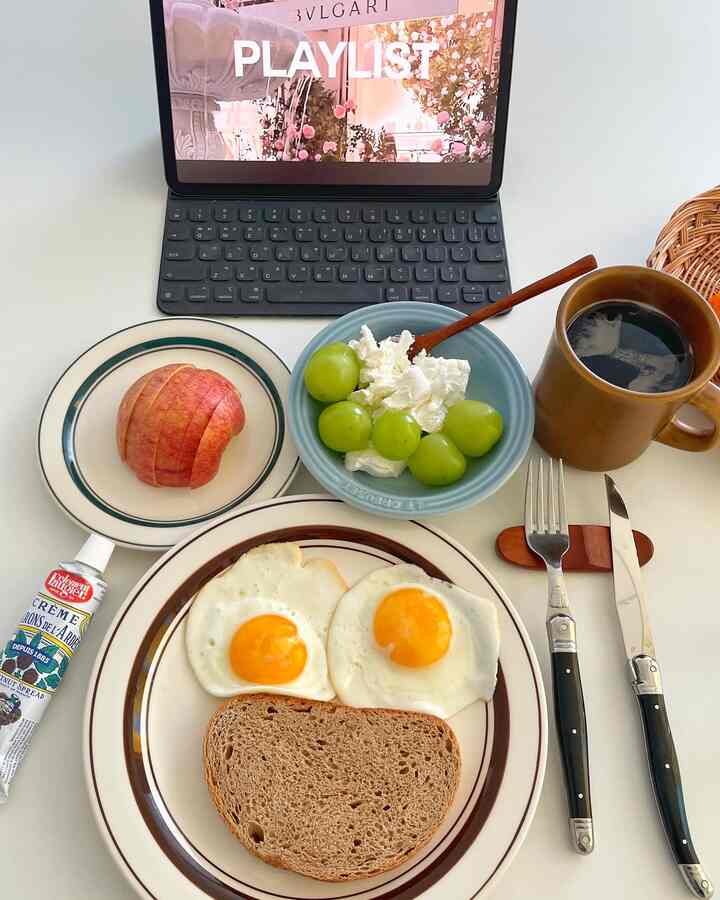 ホワイトトーンのダイニングテーブルに皿とカトラリーが整えられた朝食とホームオフィスの雰囲気のあるインテリア