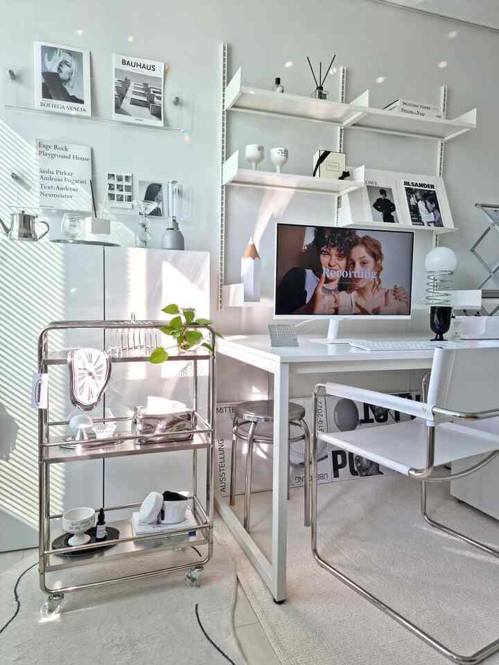 ホワイトトーンのホームオフィス、ミッドセンチュリーモダンの家具とステンレス製トロリー、棚が配置された雰囲気のあるインテリア