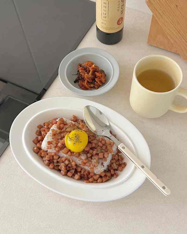 白とネイビーの色調があるキッチンのテーブルに料理とカトラリー、お茶のカップが置かれた雰囲気のある空間