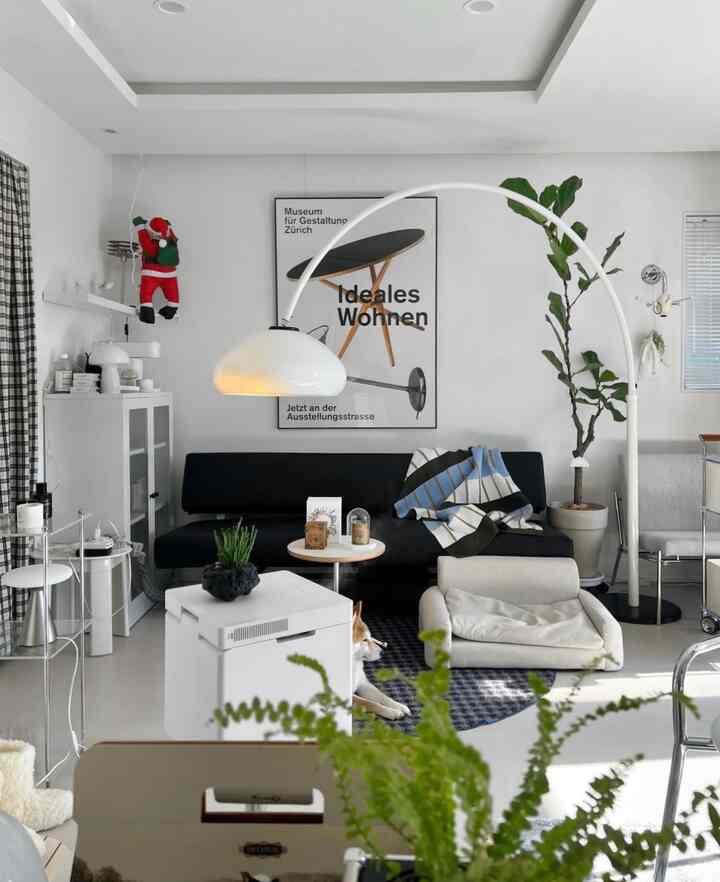 ホワイトとブラック調のモダンなリビングルーム、ソファとアーク型フロアランプ、快適な犬用ベッドが配置された落ち着いた空間