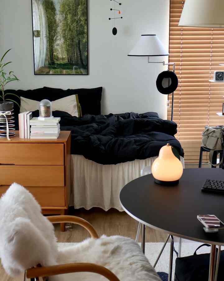 A cozy single household bedroom in black and beige tones, featuring mid-century modern furniture and a floor lamp