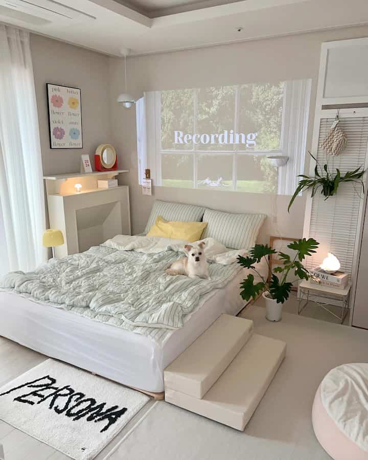 White and mint toned bedroom featuring bedding and pet steps with a dog resting, creating a cozy atmosphere