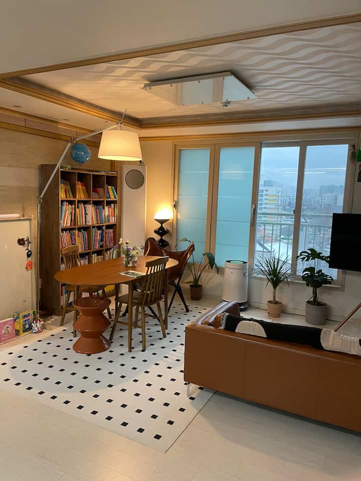 暖かい木目調とブラウン家具が配置された子供のいるリビング兼書斎の雰囲気あるインテリア