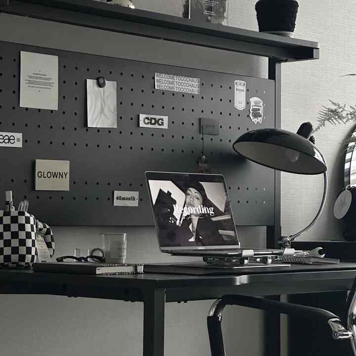 Black-toned home office space featuring a black zero desk, laptop, table lamp, and neatly arranged workspace