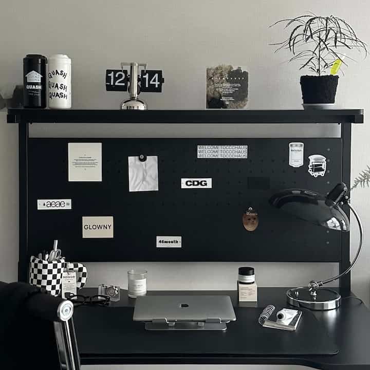 Black and white tone home office space featuring black shelf and desk with laptop and mood lighting in a modern setup