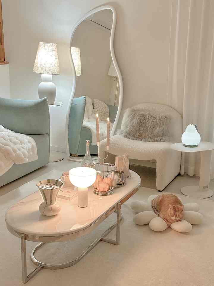 ホワイトとナチュラルトーンのリビング、ソファとアームチェア、ラグ、テーブルランプが配置された雰囲気のある空間