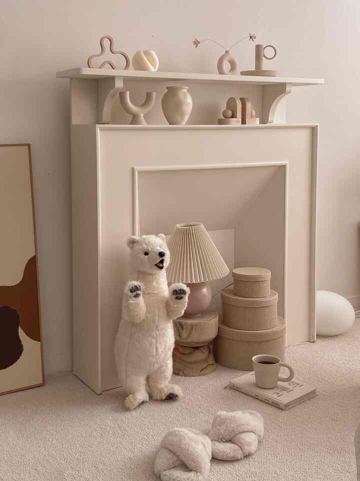 Beige and white toned space featuring a fireplace console, polar bear plush, and lamp in a cozy interior setting