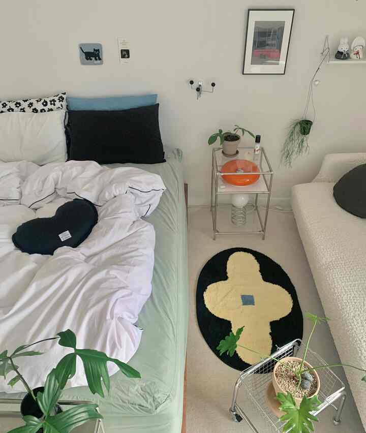 White and natural toned bedroom featuring a cozy bed, rug, and plants with a modern interior atmosphere