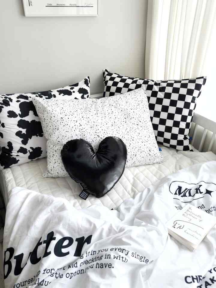 白と黒のトーンの子供部屋寝室、ミニマルなモノトーンクッションと寝具が配置された清潔感のある空間