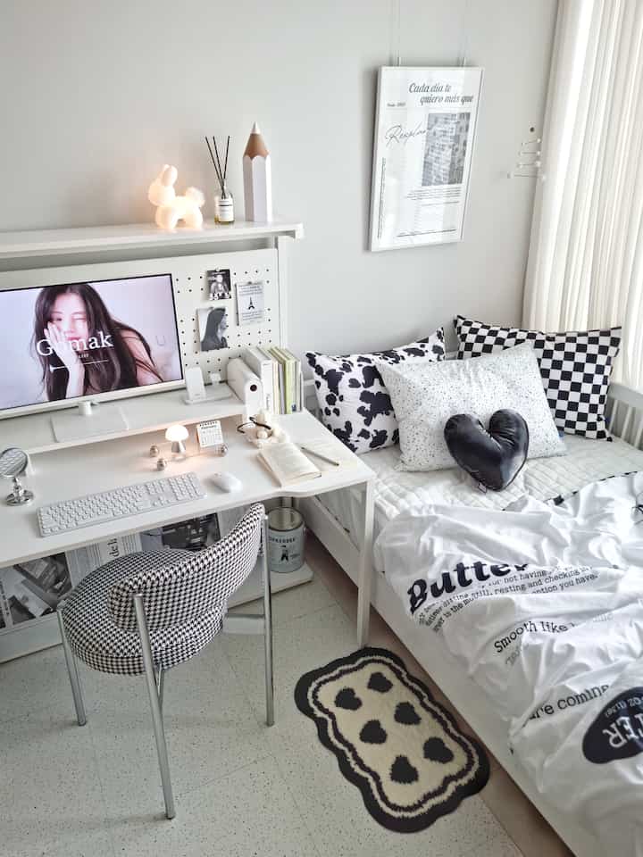 White-toned kids' room featuring a desk, bed, and patterned cushions creating a cozy and clean atmosphere