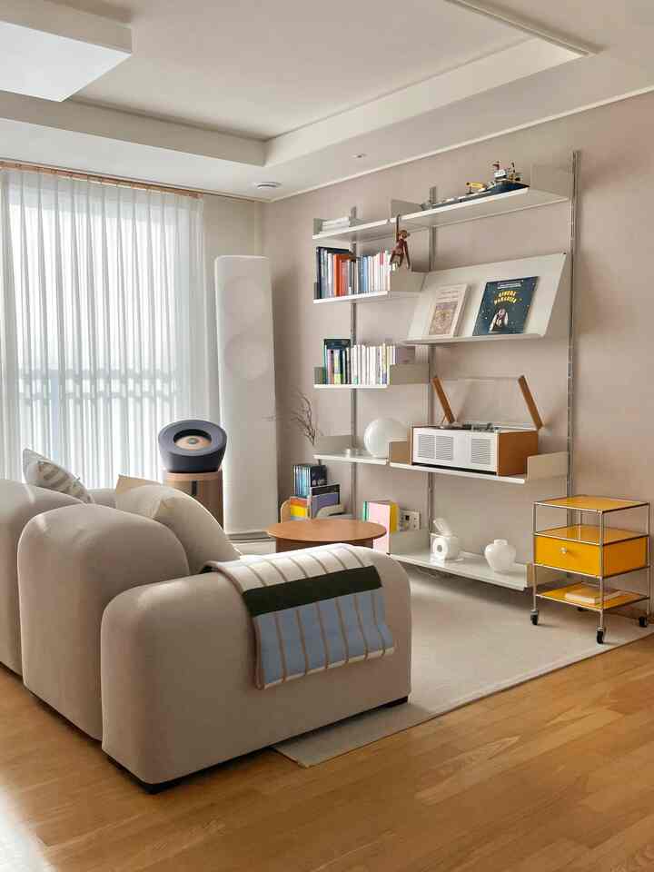 Natural beige and white toned living room featuring a modular sofa with throw, round coffee table, and modular shelving for a warm cozy atmosphere
